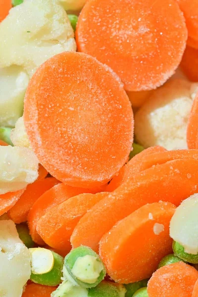 Fresh soup vegetables with carrots, peas, cauliflower and corn on white background. Frozen soup vegetables with carrots, peas, cauliflower and corn. Macro image, close-up. Vertical image. Top view