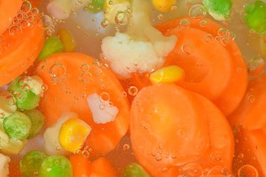 Yakın plan taze sebzeler, havuç, bezelye, karnabahar ve beyaz zemin üzerinde mısır. Havuçlu sebzeler, bezelye, karnabahar ve mısır beyaz arka planda kaynayan suda, yakın plan