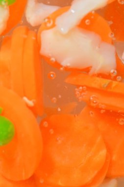 Taze sebzeli kaynar su, yakın plan. Sebzelerin havuç, bezelye, karnabahar ve su arka planında mısırla yakın plan görüntüsü. Makro kabarcıklı haşlanmış sebze dokusu.