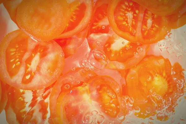 Close-up fresh slices of juicy tomato on white background. Slices of tomato in sparkling water on white background, closeup.