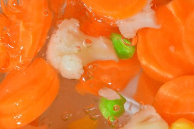 Yakın plan taze sebzeler, havuç, bezelye, karnabahar ve beyaz zemin üzerinde mısır. Havuçlu sebzeler, bezelye, karnabahar ve mısır beyaz arka planda kaynayan suda, yakın plan