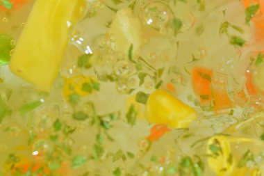 Sebze, havuç, bezelye, karnabahar, mısır, doğranmış patates ve maydanozlu suya yakından bakın. Haşlanmış sebze çorbası. Düz tasarım, üst manzara. Yatay makro