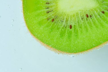 Baloncuklu kivi meyvesinin yakın plan çekimi. Yeşil olgun kivi meyvesini köpüklü suyla dilimleyin. Karbonatlı suda sulu kivi meyvesi. Makro resim.