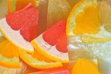 Slices of grapefruit, orange fruit and honey pomelo in water on white background. Pieces of grapefruit, orange fruit and honey pomelo in liquid with bubbles. Slices of grapefruit, orange fruit and honey pomelo in water. Macro image of fruit in water.