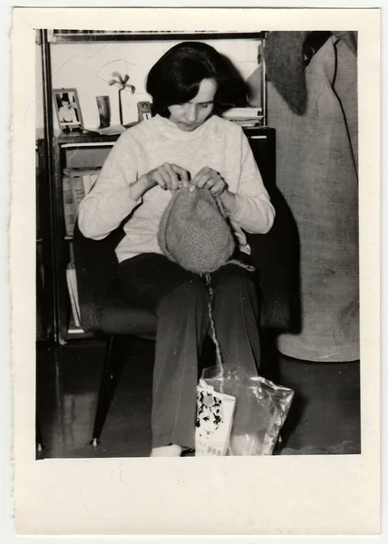 Circa 1970年代 ヴィンテージ写真は キャップを編む女性を示しています 冬の帽子を編む女性の古い黒と白の写真 1970年代における趣味と興味の概念 — ストック写真
