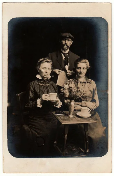 ドイツ Circa 1910年代 ヴィンテージ写真はカップ 新聞やパイプで男と女のポーズを示しています アンティーク黒と白のスタジオの肖像画 — ストック写真