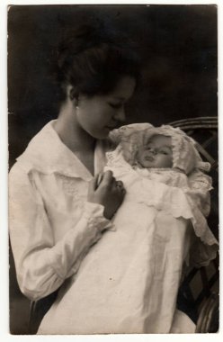 ALMANY - 25 Nisan 1918: Vintage fotoğraf kundağa sarılmış bebekli bir kadın gösteriyor. Retro siyah beyaz stüdyo fotoğrafçılığı.