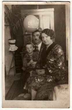 PRAHA (PRAG), CZECHOSLOVAK REPUBLIC - 15 Mart 1931: Vintage fotoğraf oturma odasında aile gösterir. Çocuk hava topu tutuyor, şişme top. Retro siyah beyaz fotoğraf. Çember 1930 'lar.