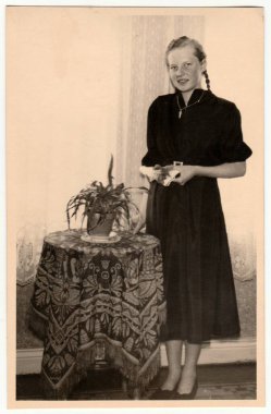 CZECHOSLOVAK SOSYALİK REPUBLIC - CIRCA 1950 'ler: Klasik fotoğraf oturma odasındaki masada genç bir kızın pozunu gösteriyor. Retro siyah ve beyaz fotoğrafçılık.