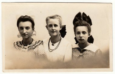 HAMBURG, GERMANY - CIRCA 1940 'lar: Fotoğraf stüdyosunda bir grup kız poz veriyor. Kızlar saç kurdelesi ve kolye takıyor. Boncuk dizisi. Sepya etkisi olan siyah ve beyaz geçmişe dönük fotoğrafçılık. 1940 'larda..