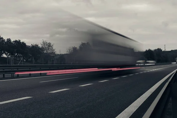 黄昏时 一辆卡车在高速公路上行驶 公路上的运动模糊了 卡车的夜间拍摄 国际运输和物流的概念 几乎是单色图像 — 图库照片