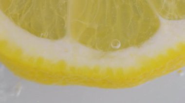 Su kabarcıklarında bir dilim olgun limon. Mayonezli limon dilimi ve soda. Karbonatlı sudaki limon dilimine yakın plan.