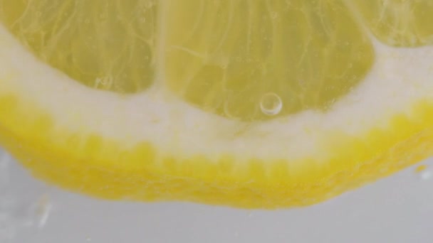 一片成熟的柠檬在水泡里 柠檬片在闪闪发光的水中的宏观镜头 碳化水中柑橘片的特写 — 图库视频影像
