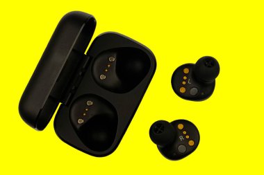 Kablosuz stereo kulaklıklar. Siyah kablosuz kulaklıklar ve şarj çantası. Kulaklık ya da kulaklık ve şarj kutusu ile sarı arka planda izole edilmiş kulaklıklar için şarj edilebilir pil.