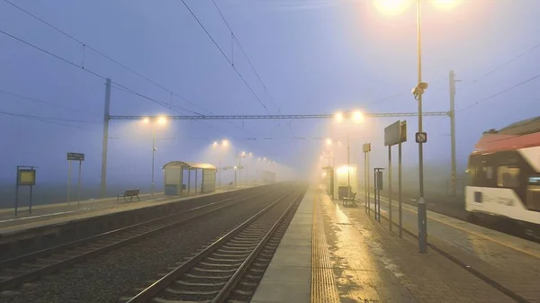 Night train in the fog. Station in fog and darkness. Passage of express train in fog and darkness. Concept of transport problems, suburban transport and fast train transport.
