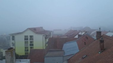 Çatılardan şehrin sisli manzarası görünüyor. Şehrin puslu havadan görünüşü. Kasaba sisli.