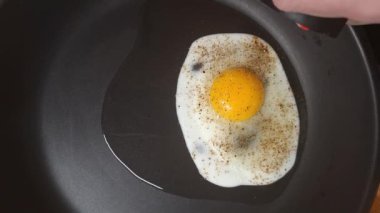 Tavada yumurta oksusu gözü var. Kızartma tavasındaki mükemmel boğa gözü yumurtasına baharat katmak. Kızartılmış ve baharatlı, güneşli tarafı pişmiş yumurta. Ev yemeği, aşçılık ve gastronomi kavramı..