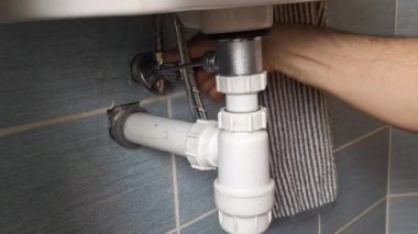 Tesisatçı lavabonun altındaki vanayı açar. Tesisatçı elleri lavabonun altındaki su vanasını açar. Küçük ev onarımı, temizlik, DIY, bakım, el sanatları