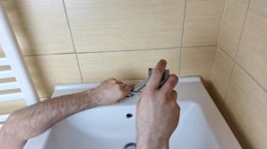 Tesisatçı lavabodan musluğu çıkarır. Tesisat işi. Ev bakımı, küçük tamirat ve bakım konsepti.