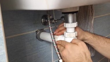 Bir muslukçu, banyo lavabosunun altındaki sifondaki contaları çıkarır. Tesisatçıların elleri sifondaki contaları çıkartıyor. Evdeki küçük onarımlar, oda servisi, DIY, bakım, el sanatları