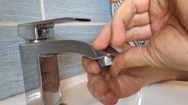 Tesisatçı musluğa bir havalandırma cihazı yerleştirir. Muslukçuların elleri musluğu tamir eder. Küçük ev onarımı, temizlik, DIY, bakım, el sanatları, inşaat.