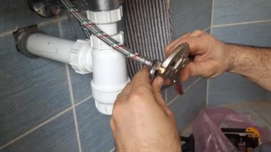 Bir muslukçu bir su hortumuna fiş takıyor. Tesisatçı elleri, metal örgülü boruya boş fişi takıyor. Evdeki küçük onarımlar, oda servisi, DIY, bakım, el sanatları