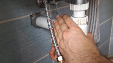 Bir muslukçu lavabonun altındaki sifona mühür takıyor. Tesisatçı elleri lavabonun altındaki sifona conta yerleştiriyor. Evde küçük tadilatlar, oda temizliği, DIY, bakım