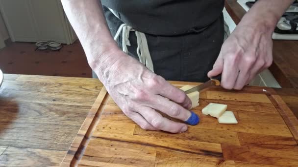 シェフはチーズをキューブに切った マンスの手はチーズをキューブに切った シェフの指はプラスターで包まれた 料理のコンセプト 自宅のキッチンからの映像 — ストック動画