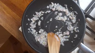 Altın sarısına kadar soğan karıştır. Erkekler kaşıkla soğan dilimlerini karıştırır. Ev yemeği, gastronomi ve aşçılık kavramı.