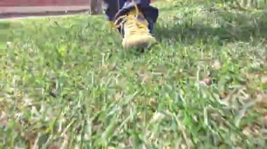 Sarı ayakkabılar çimenlerde yürüyor. Sarı spor ayakkabılar çimlerin üzerinde. Spor ve sağlıklı yaşam tarzı kavramı...