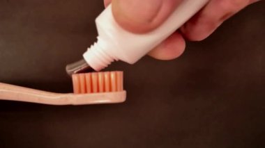 Siyah bir diş macunu diş fırçasına sıkıştı. Diş fırçasına bastırılmış diş macununun yavaş hareketi. Siyah arka planda kömür tozu ve diş fırçasıyla doldurulmuş siyah diş macunu. Yakın plan..