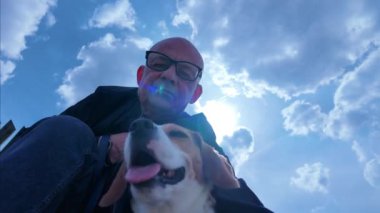 Bir efendi ve av köpeği dışarıda oturuyor. Aşağıdan yukarıya doğru bak. İtaatkar köpek ve köpek sevgisi kavramı.