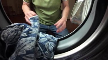 Bir adam kirli çamaşırları çamaşır makinesine koyar. Bir erkeğin elleri çamaşır makinesine çamaşır koyar. Evdeki erkek kavramı..