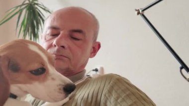 Efendi köpeğini okşar. Köpek esniyor. Köpek minnettarlıkla efendilerinin yüzünü yalıyor. Bir köpeğin sahibine olan sevgisi kavramı. Yakın plan..