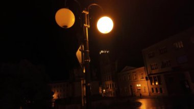 A view of the city at night in the rain. Raindrops and a lit street lamp in a town.