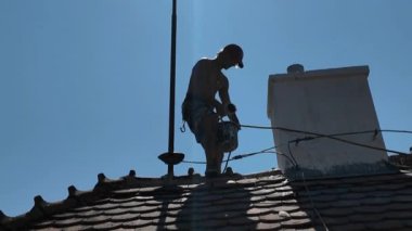 Bacadaki çatı işçisi. Güvenlik ipi ve özel koşum takımı olan çatı işçisi. Çatı işçisi emniyet kemerini adapte ediyor. Yükseklerde çalışırken iş güvenliği kavramı.