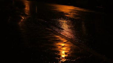 Gece yağmuru ve yağmur damlaları su birikintisine düşüyor. Sağanak yağmur ve hafif su birikintisi.