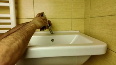 Bir tesisatçı yeni bir musluk takıyor. Yeni bir musluk takıyorum. Evdeki küçük tamirat kavramı.