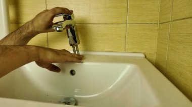 Bir tesisatçı yeni bir banyo musluğu takıyor. Yeni bir su musluğu kurulumu. Evdeki küçük tadilat kavramı.