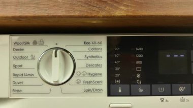 Çamaşır makinesinin programlarını açıyorum ve ayarlıyorum. Farklı programlar arasında geçiş. Bir erkek el çamaşır makinesinin döngüsünü ayarlar. Ev yıkama konsepti.