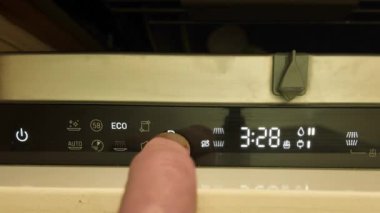 Bulaşık makinesinin kontrol panelinde bir erkek parmak. Bulaşık makinesinin programını değiştiriyorum. Bulaşık makinesinde aydınlatılmış dijital ekran düğmeleri. Bulaşık makinesinin kapısını kapatıyorum..