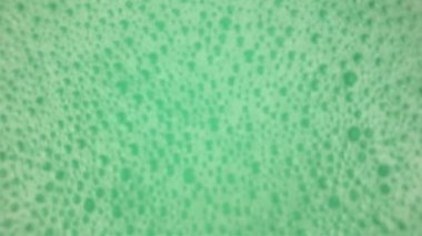 Baloncuklu hafif sallanan turkuaz yeşil yüzey. Banyo köpüğüyle sallanan su yüzeyi. Kısmen bulanık sabun köpükleri. Sağlık, kaplıca ve kendine bakım kavramı.