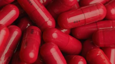 Bir yığın ilaç, haplar. Kırmızı ilaç hapları. Arka planda dönen bir ilaç. Tıbbın aşırı kullanımı kavramı.