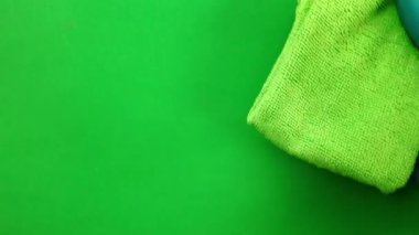 Kadının eli pencere camını siler. Lastik eldivenli bir el pencere camını temizler. Eller yeşil arka planda. Temizlik ve ev işi kavramı.