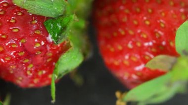 Koyu bir arka planda kırmızı çilek manzarası. Olgun kırmızı böğürtlenlerin yakın çekimi. Arka planda dönen çilekler. Meyve kavramı, sağlıklı yiyecek ve sağlıklı yaşam tarzı..