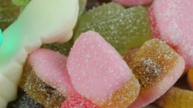 Jelatin tatlılar. Dönen bir yüzeyde jöle şekerlemeleri. Sakızlı meyve tatlısı. Makro atış. Çok renkli bir arka plan. Çocukluk kavramı, tatlılar ve şekerlemeler