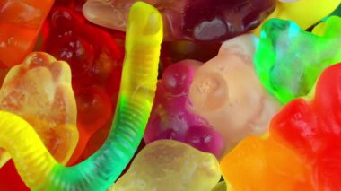 Jelatin tatlılar. Dönen bir yüzeyde jöle şekerlemeleri. Sakızlı meyve tatlısı. Makro atış. Çok renkli bir arka plan. Çocukluk kavramı, tatlılar ve şekerlemeler