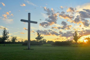 A large Christian cross in the scenery of a landscape. A Christian cross lighted by the setting sun. The concept of religion and Christianity