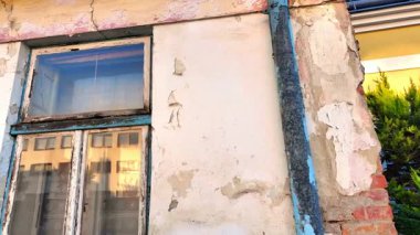 Eski bir evin yıpranmış görüntüsü. Evin eski cephesini, pencerelerini ve kapılarını görüyorum. Emlak acenteleri kavramı, inşaat sektöründe yeniden yapılanma. Yavaş çekim