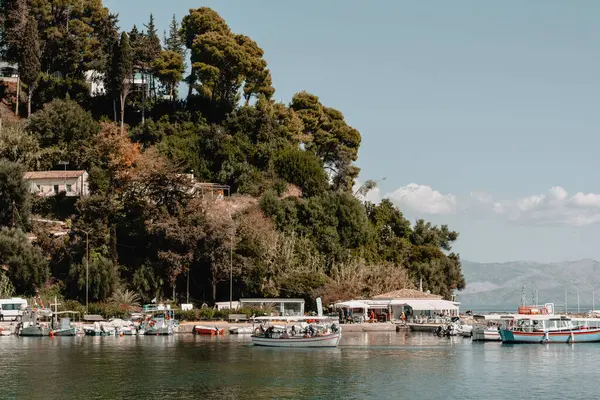ギリシャのコルフ 多くのボートがドッキングされているボートドックとビーチの海岸 緑の木の丘 — ストック写真